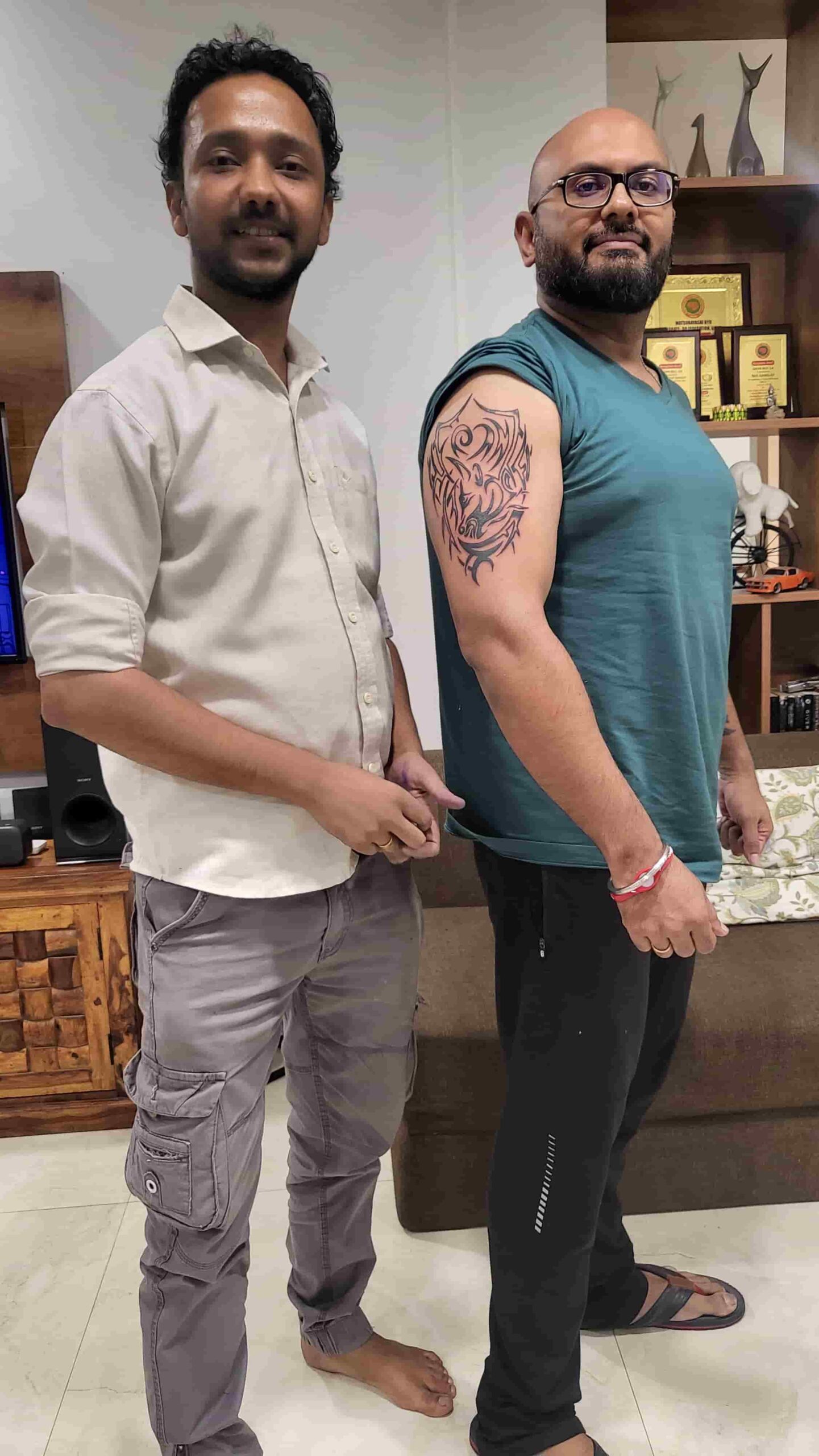 Male customer showing a black tribal-style upper-arm tattoo beside the artist