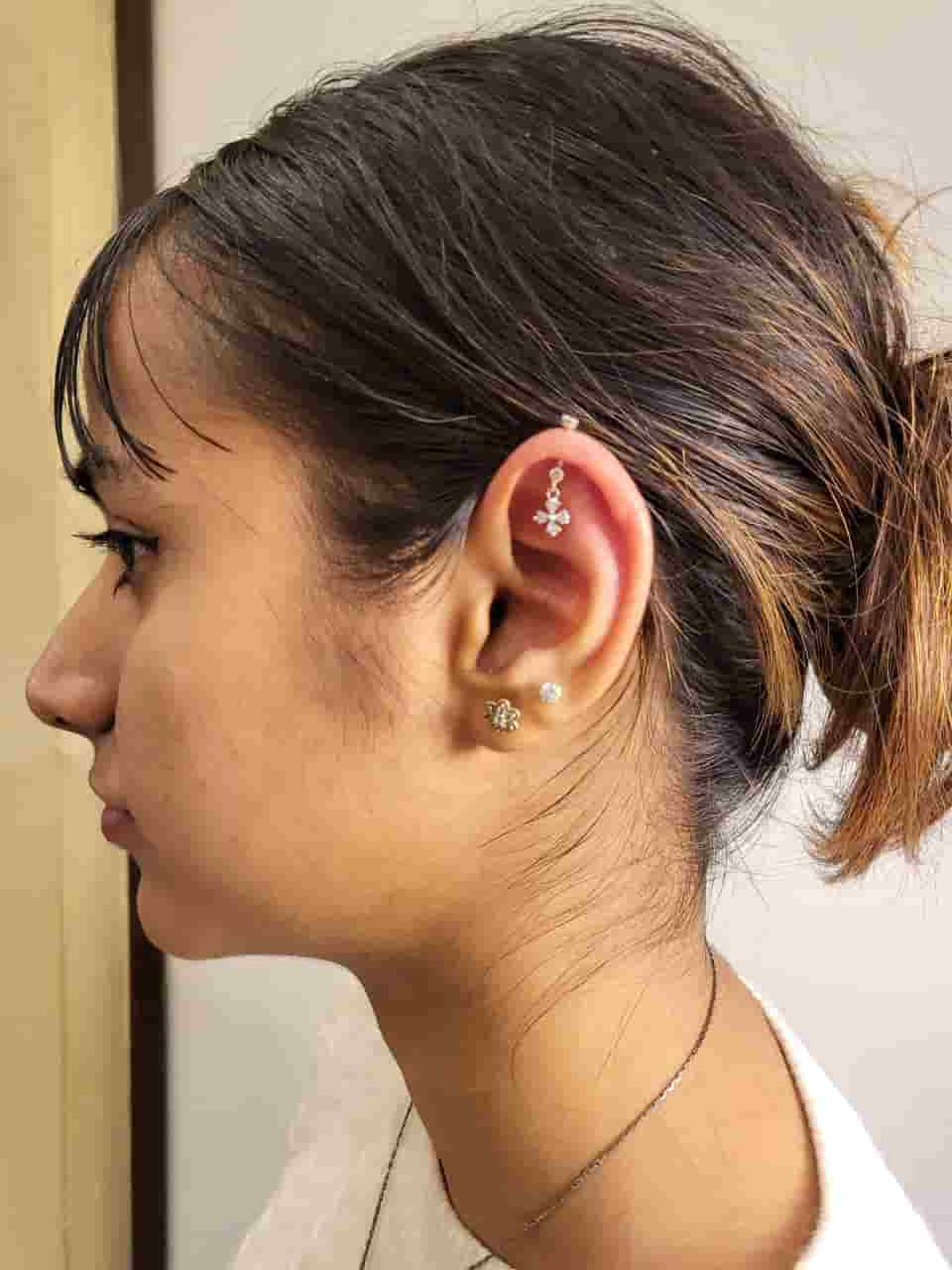 Woman wearing upper-ear cartilage and lobe jewellery after a piercing appointment